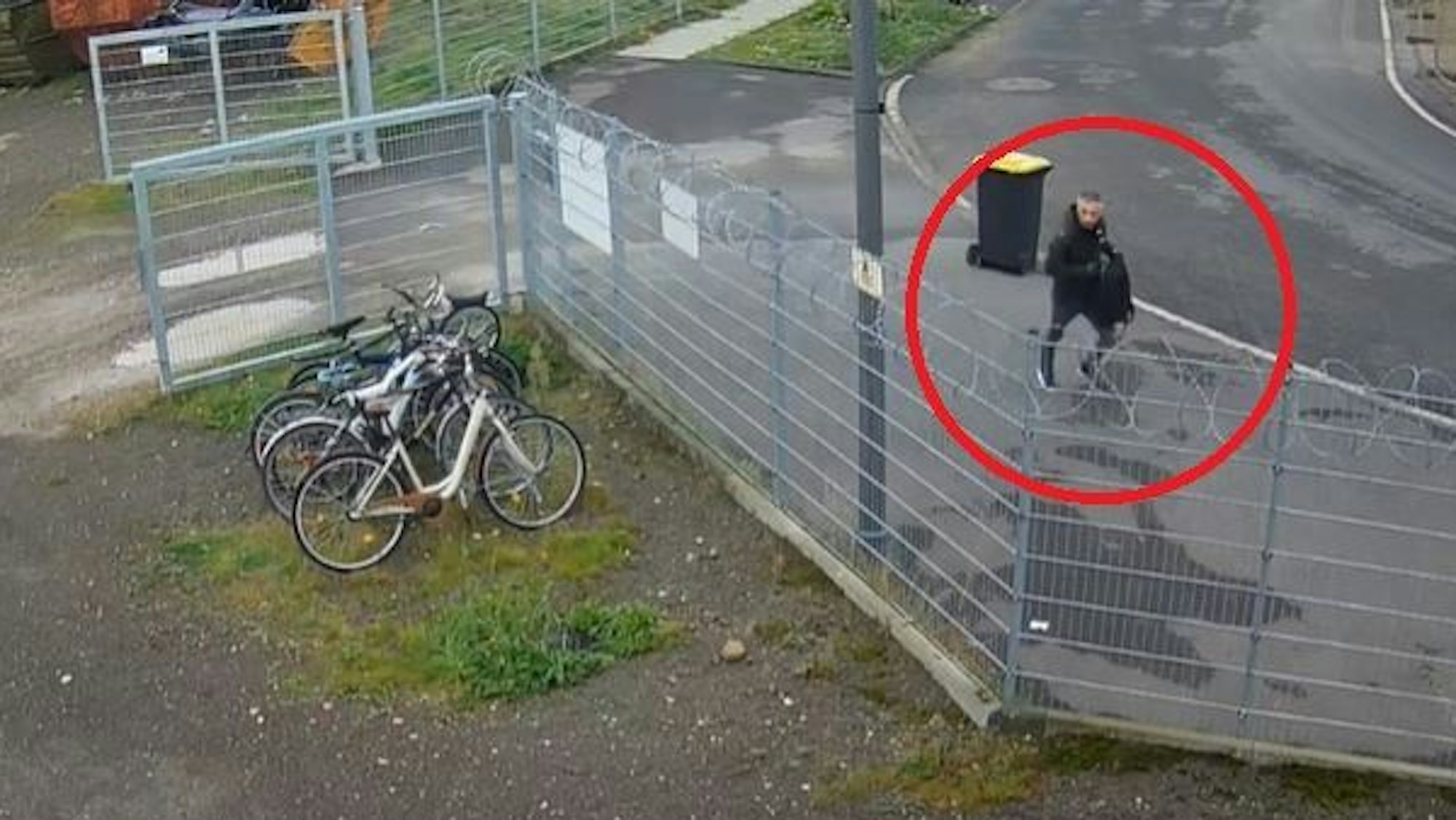 Screenshot von einer Überwachungskamera. Zu sehen ist ein Mann in schwarzen Klamotten, der von einem Grundstück wegläuft.