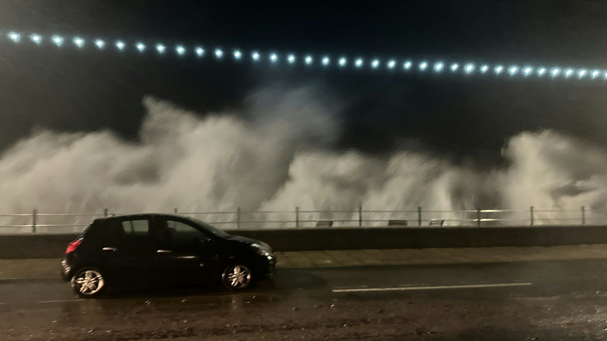Ein Auto fährt an der Küste von Penzance im Süden Großbritanniens eine Straße entlang. Im Hintergrund sind hohe Wellen zu sehen, die durch Orkantief Ciarán ausgelöst wurden. Der Sturm verursachte in Frankreich Wellen mit einer Höhe von teilweise mehr als zehn Metern.