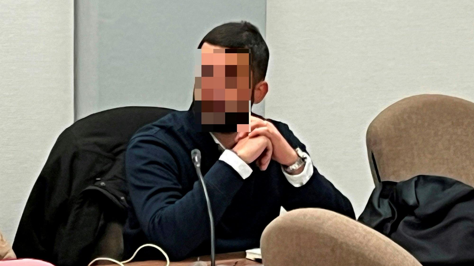 Ein Mann sitzt mit verschränkten Händen im Gerichtssaal.