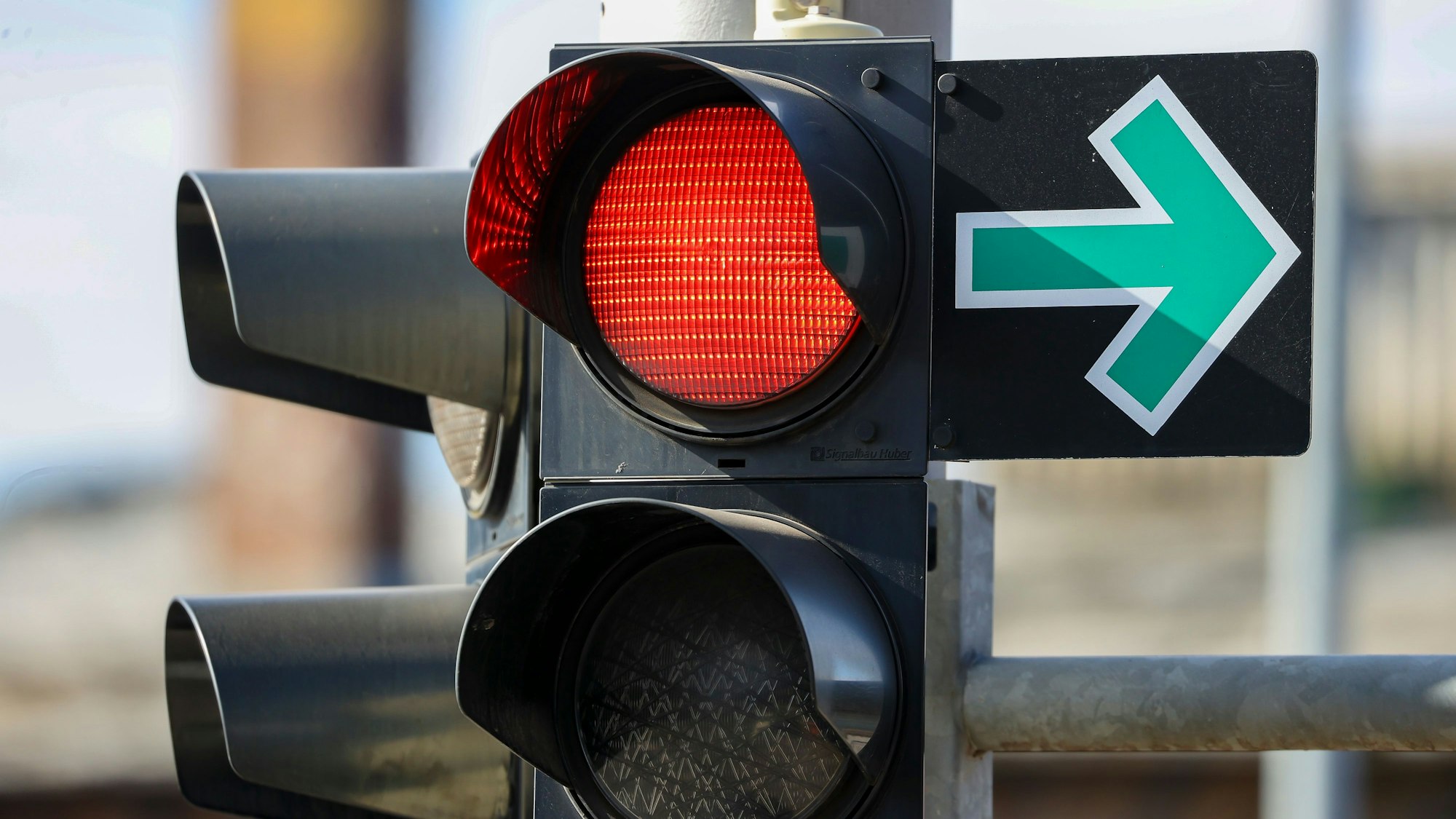 Ein grüner Pfeil hängt neben einer roten Ampel an einer Kreuzung und erlaubt das Abbiegen trotz Rotlicht.