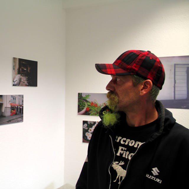 Fotograf Reiner betrachtet seine Ausstellungsmotive im Offenen Treff der Oase.