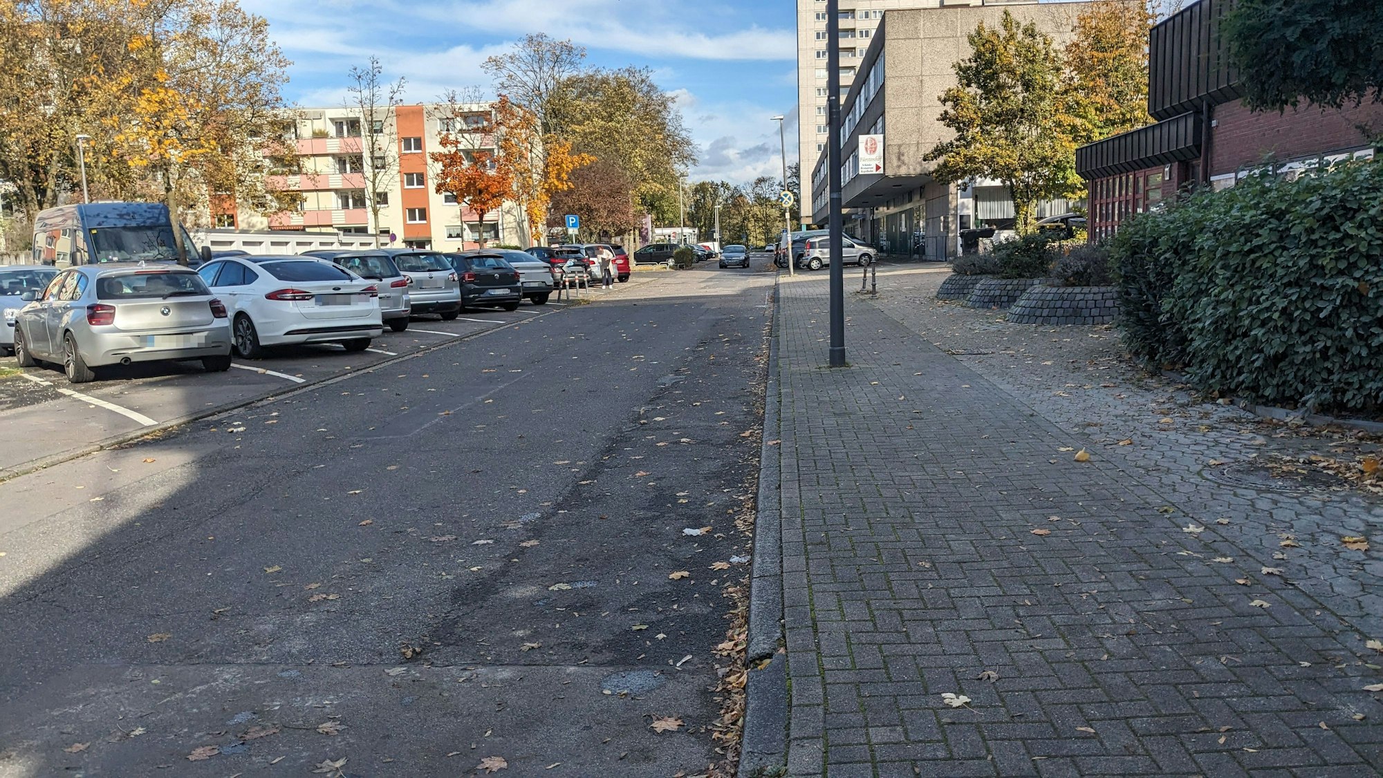 Eine Straße in Köln Heimersdorf, links parken Autos.