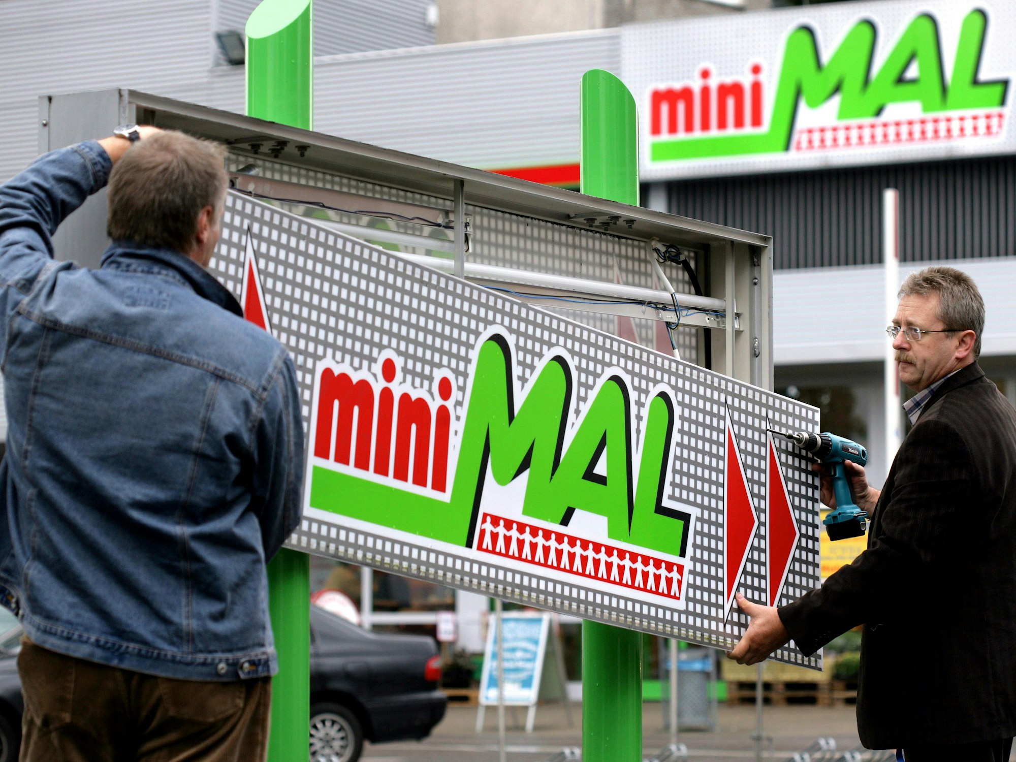 Mitarbeiter einer Beschriftungsfirma entfernen am Donnerstag (24.08.2006) vor einem miniMal Supermarkt in Köln das Logo.