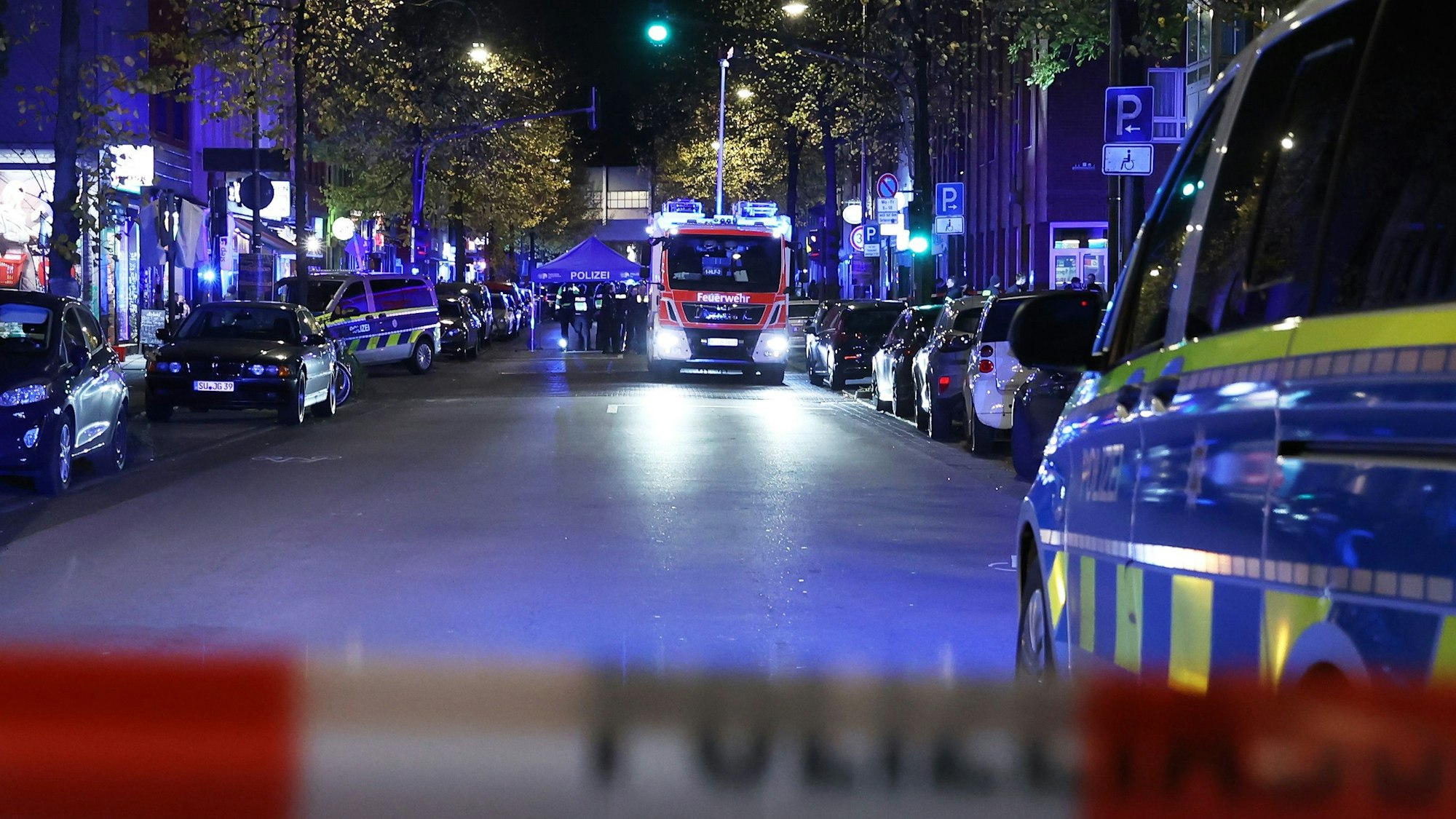 Ein Feuerwehrauto und ein Polizeizelt stehen in der Nacht auf der Venloer Straße.