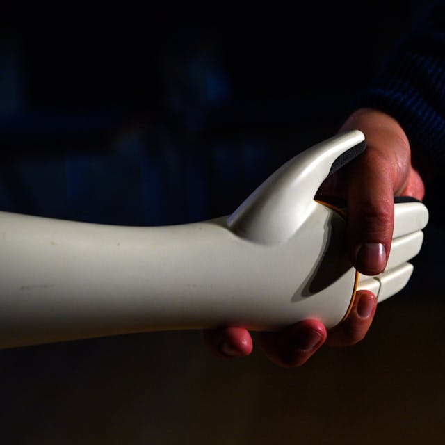Eine menschliche Hand greift die Hand eines humanoiden Roboters.