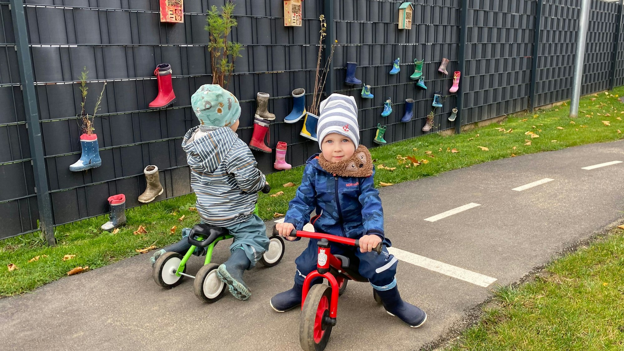 Zwei Kinder auf Dreirädern fahren aneinander vorbei.