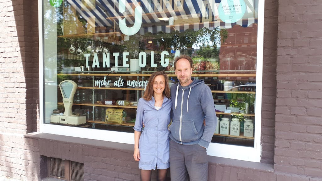 Olga und Gregor Witt vor ihrem Laden in Köln-Sülz, sie stehen Arm in Arm vor dem Schaufenster.
