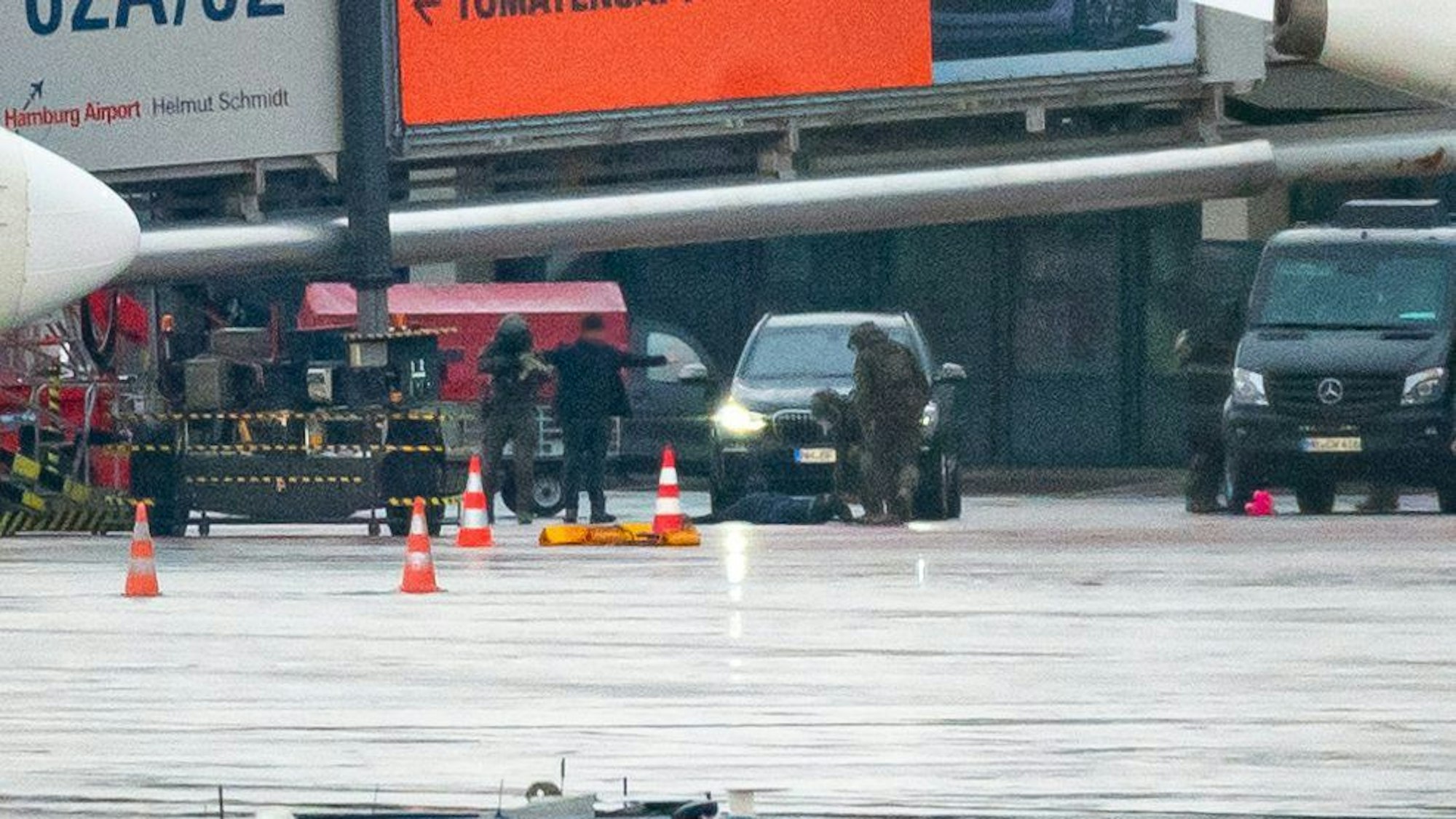 Hamburg: Der Geiselnehmer liegt am Flughafen vor einem Fahrzeug auf dem Boden und wird von Spezialkräften der Polizei in Schach gehalten.