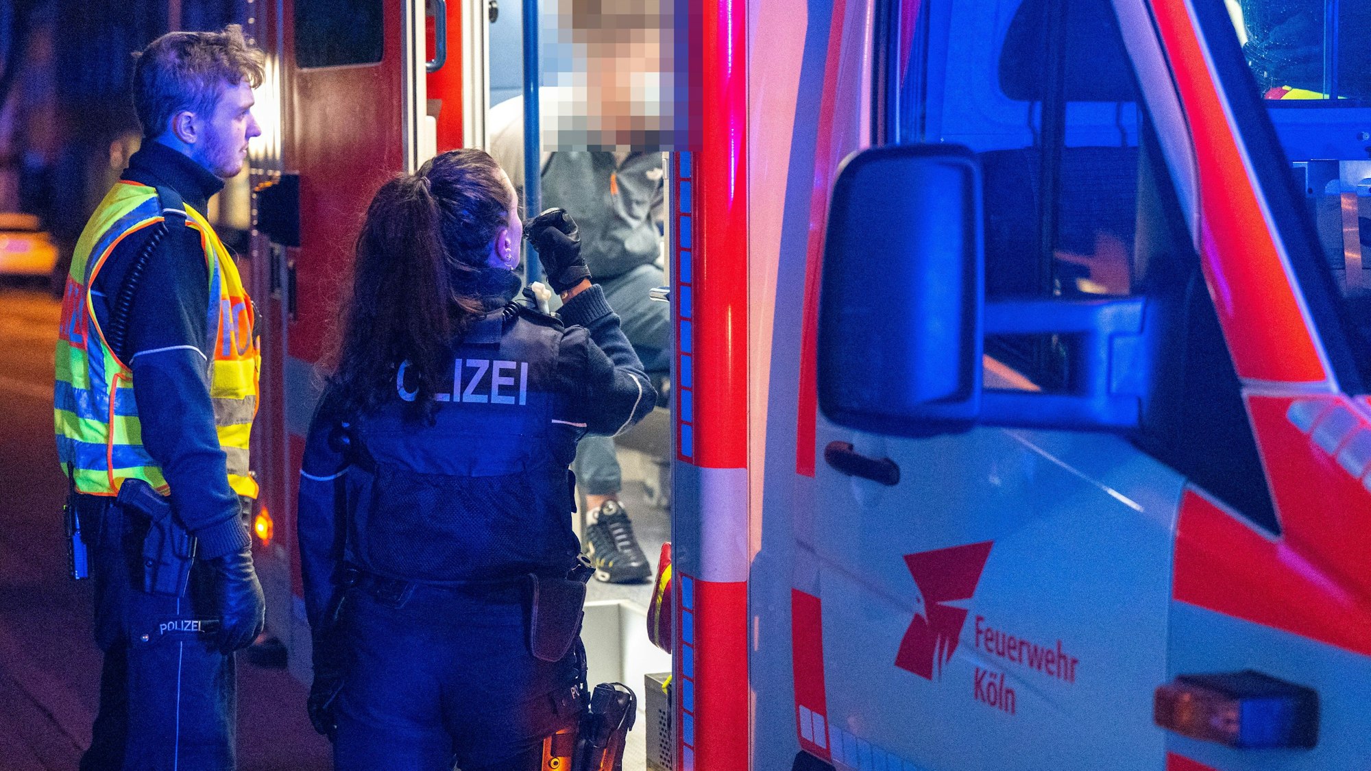 Die Kölner Polizei befragt einen Mann, der in einem Rettungswagen behandelt wird.