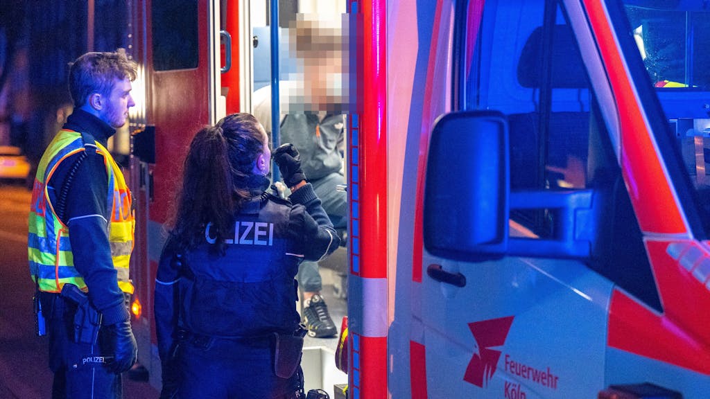 Die Kölner Polizei befragt einen Mann, der in einem Rettungswagen behandelt wird.