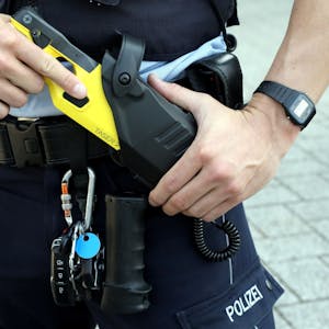Ein Polizist zieht einen Taser aus dem Einsatzgürtel.