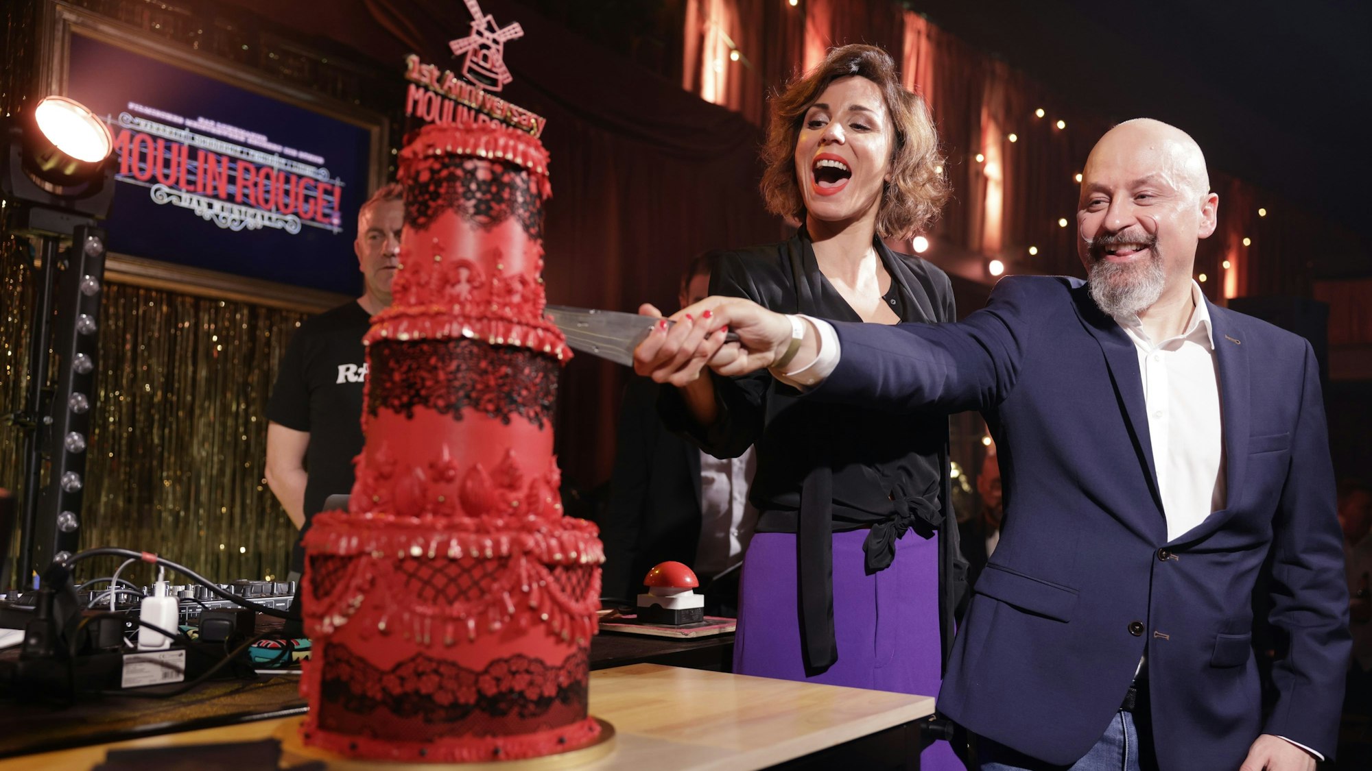 „Moulin Rouge“-Hauptdarstellerin Sophie Berner und Hauptdarsteller Gavin Turnbull schneiden die Geburtstagstorte an.