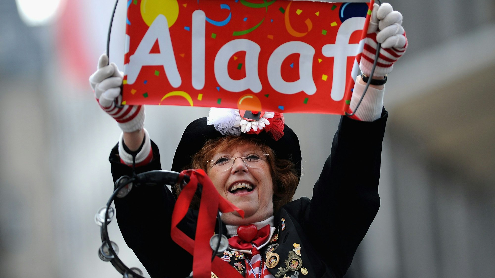 Frau hält ein Schild mit Alaaf im Kölner Karneval hoch