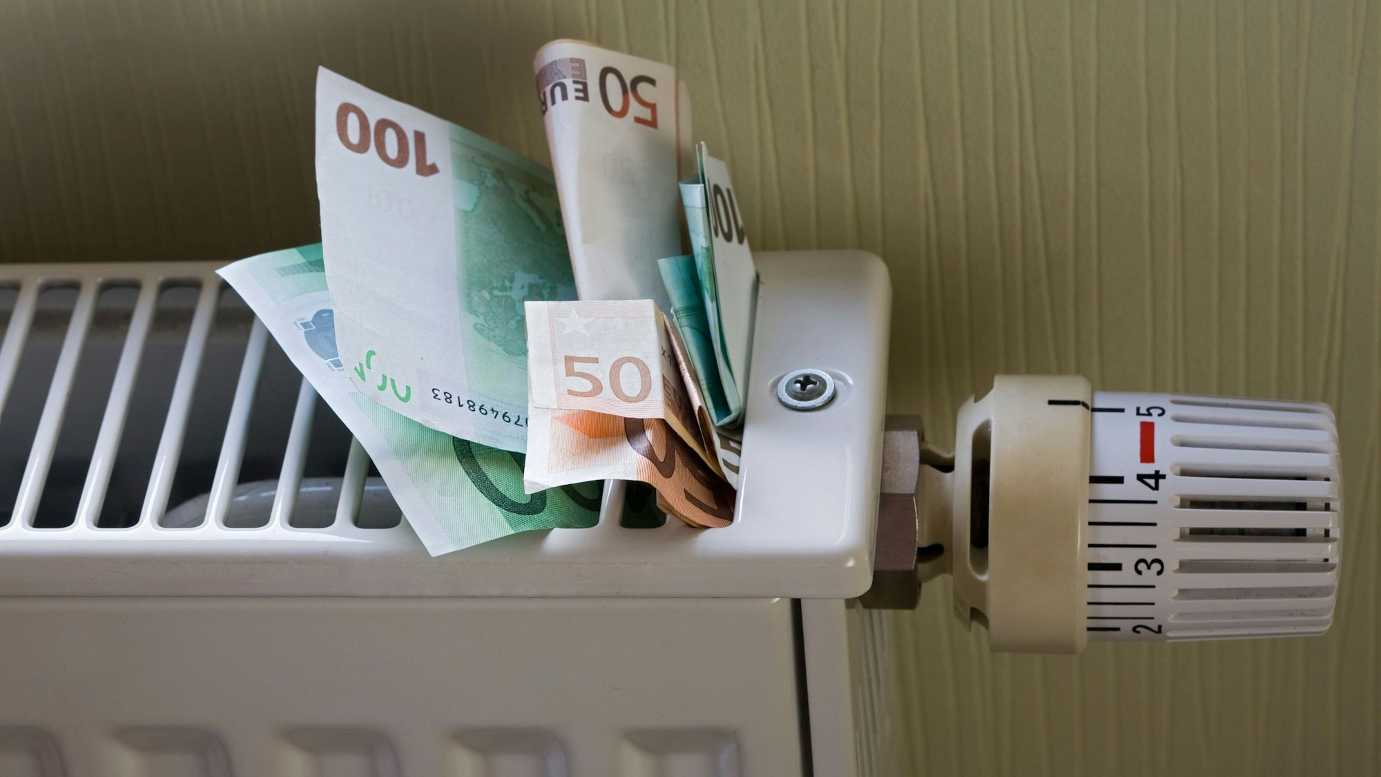 Euro-Banknoten stecken in einem Heizkörper