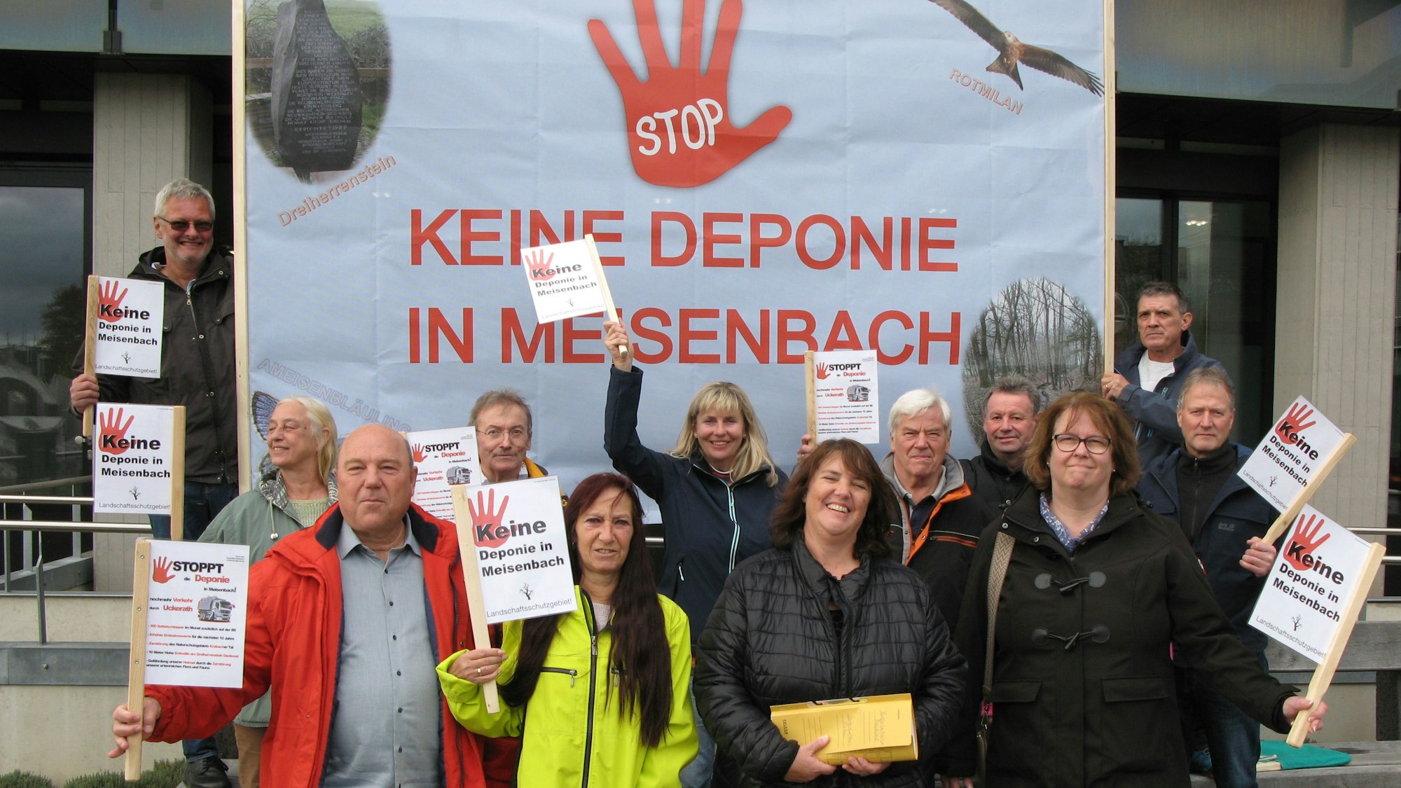 Zwölf Männer und Frauen halten Schilder und ein großes Transparent hoch, auf dem steht: Stop, keine Deponie in Meisenbach.