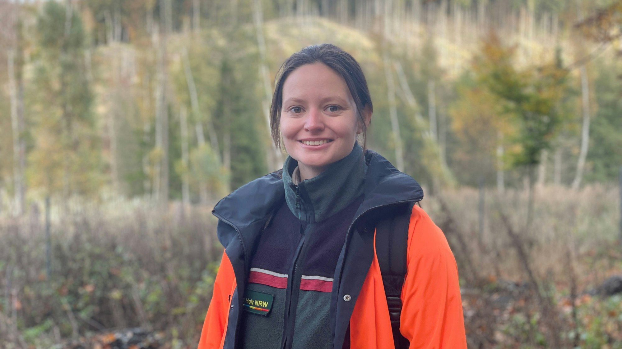 Catharina Schmidt vom Forschungsnetzwerk Wald steht auf einer kahlen Waldfläche, im Hintergrund sind Stämme und einige Bäume zu sehen.