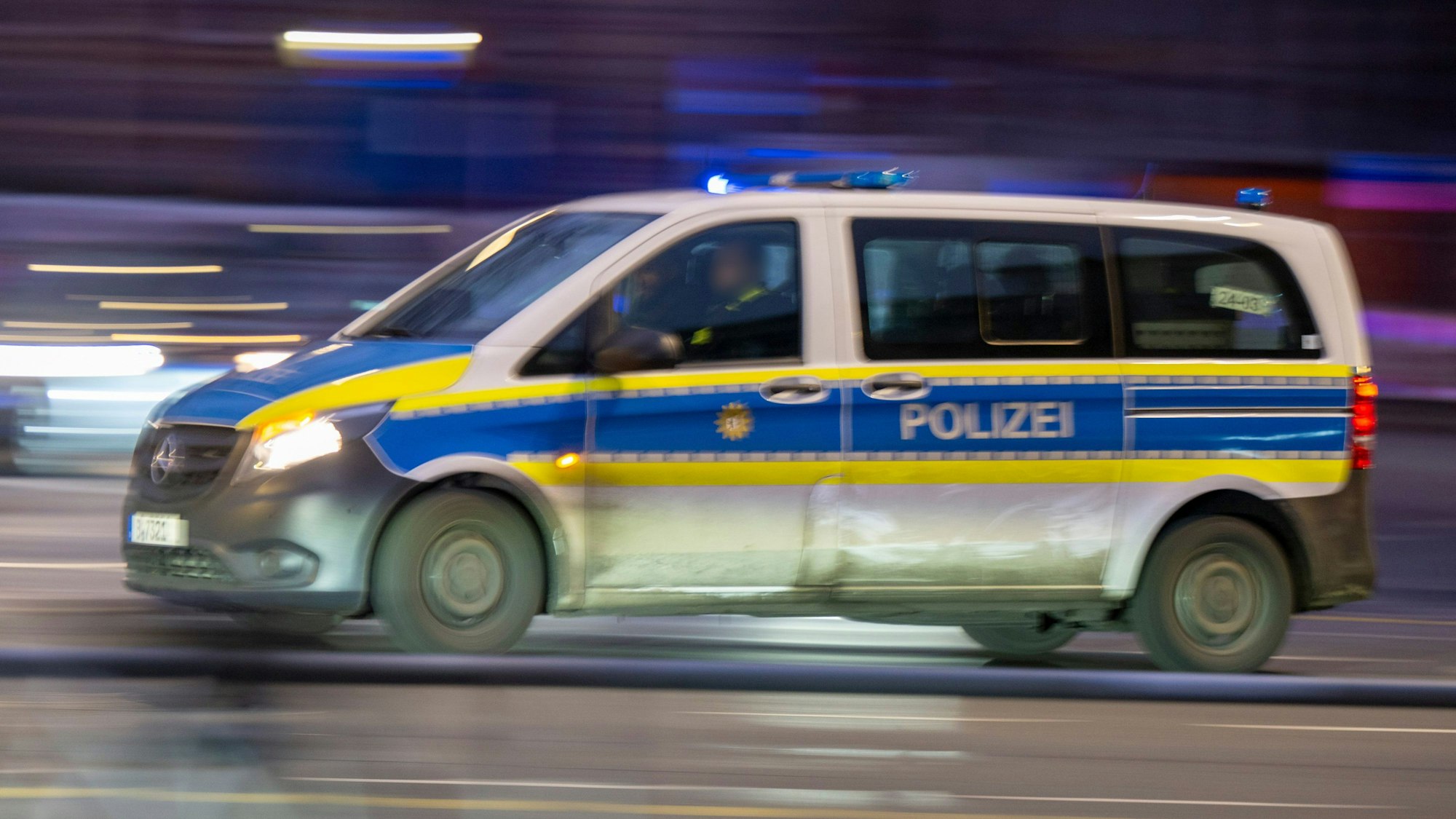 Ein Polizeiauto fährt mit Blaulicht zu einem Einsatz (Aufnahme mit Wischeffekt und Langzeitbelichtung).
