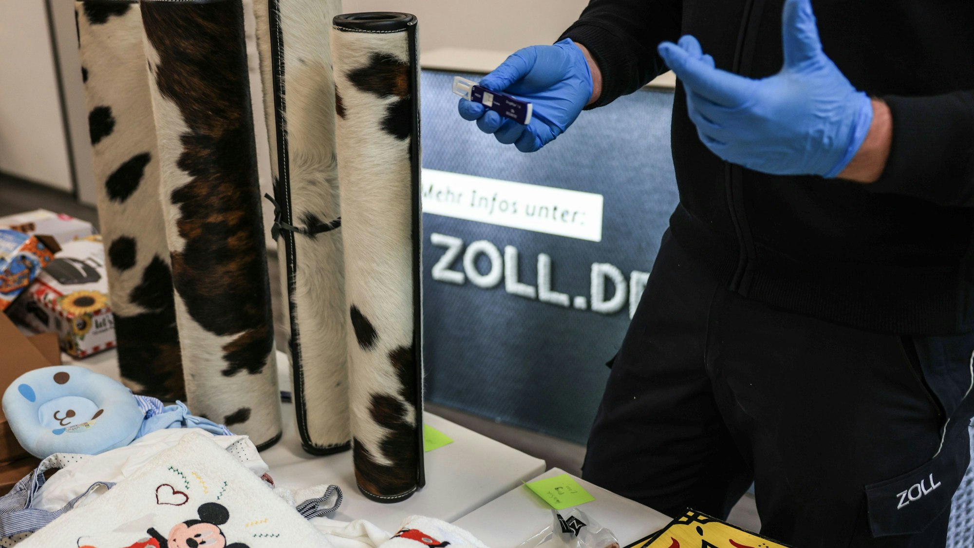 Ein Mitarbeiter des Hauptzollamtes Köln zeigt ein Drogentestgerät hinter verschiedenen Drogenverstecken. (Symbolbild)