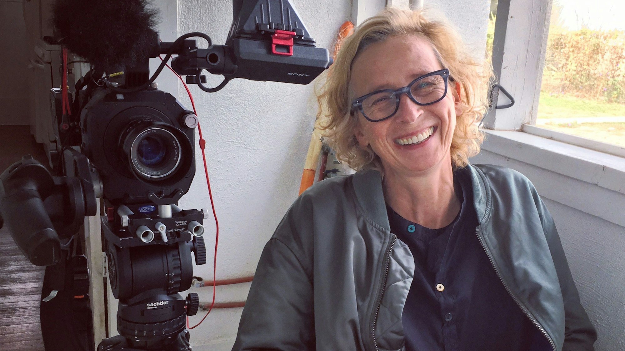 Die Fernsehjournalistin und Dokumentarfilmregisseurin Claudia Müller im Porträt. Neben ihr steht eine Kamera.