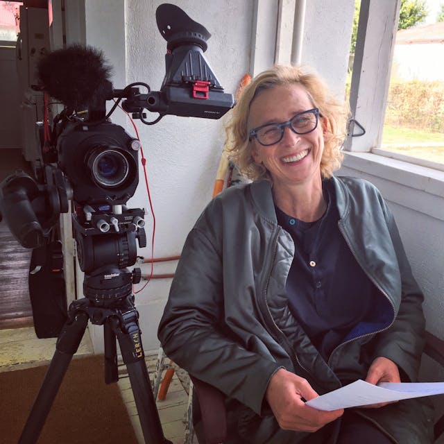 Die Fernsehjournalistin und Dokumentarfilmregisseurin Claudia Müller im Porträt. Neben ihr steht eine Kamera.