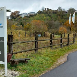Ein Schild an der Einfahrt zum Ferienpark in Kronenburg, im Hintergrund ist das Dorf zu sehen.