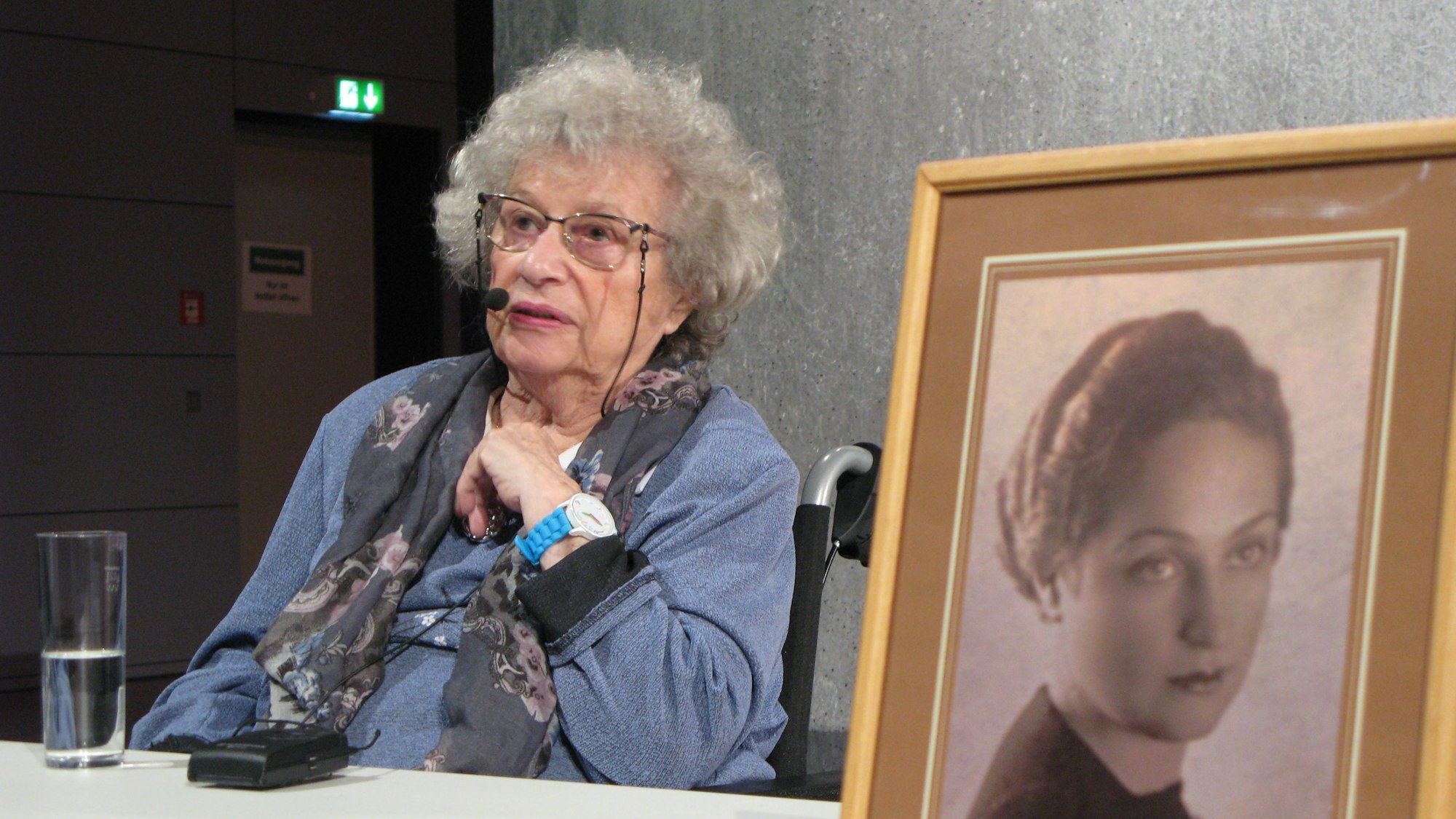 Tamar Dreifuss sitzt an einem Tisch, vorn steht eine gerahmte Fotografie ihrer Mutter.