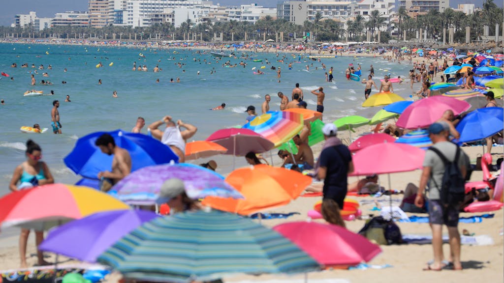 Urlauberinnen und Urlauber tummeln sich am Strand auf Mallorca.