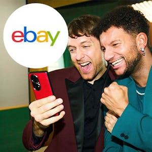 Zwei Männer schauen erfreut auf ein Handy.