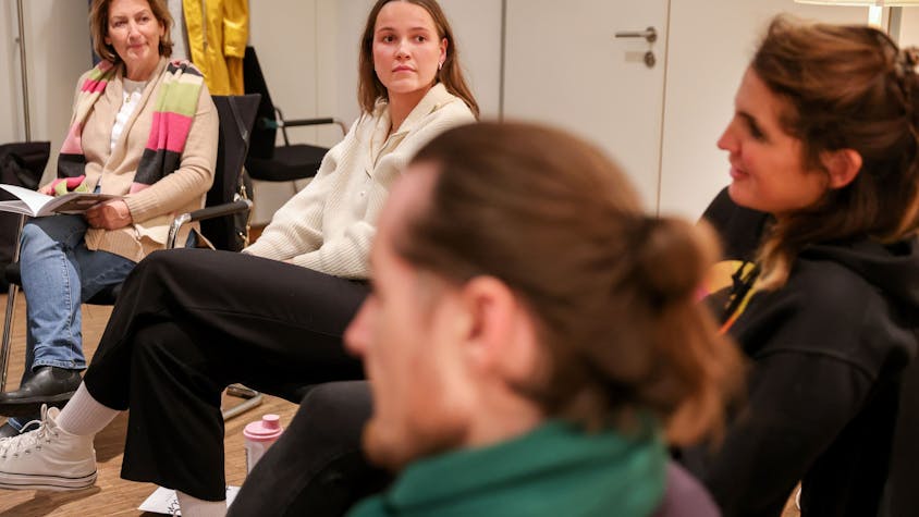 Emilie Vogeler trägt einen weißen Pulli und eine schwarze Hose und sitzt mit anderen Ehrenamtlichen bei einer Gesprächsrunde des Hospizvereins Mülheim.