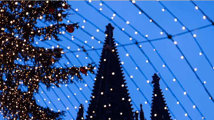 Köln: Die Domspitzen sind hinter Beleuchtung des Weihnachtsmarkts auf dem Roncalliplatz zu sehen.
