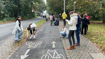 Auf dem Bild sind Schüler zu sehen, die einen Radweg ausmessen.