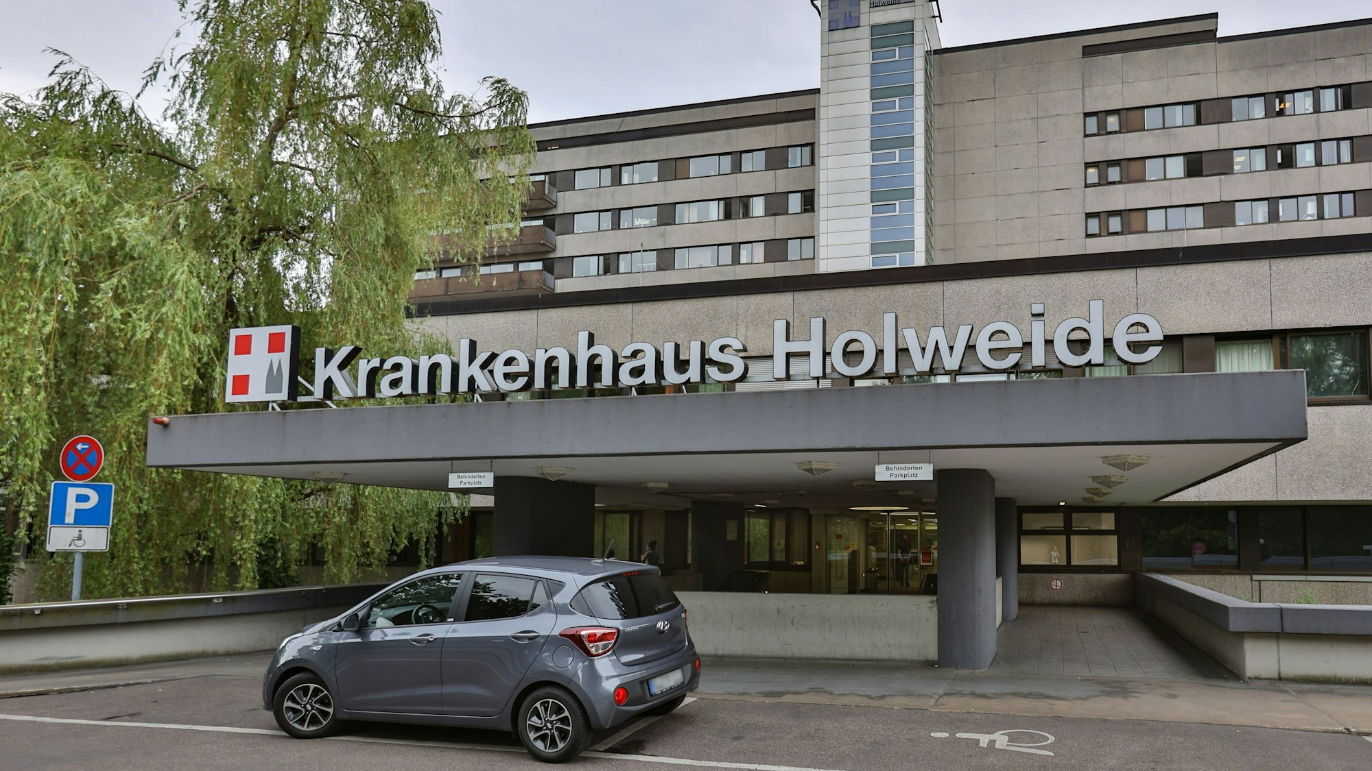 Das Bild zeigt ein Krankenhaus, vor dem ein Auto steht.