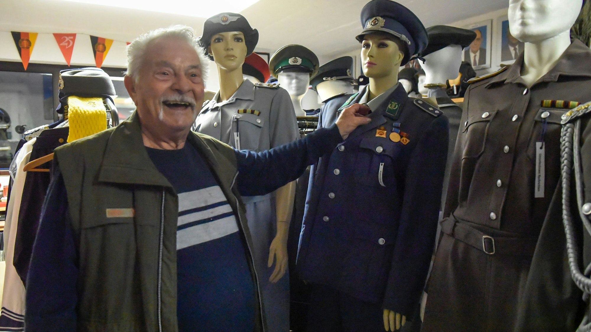 Das Foto zeigt Armin Schmitt vor Uniformen aus der ehemaligen DDR.
