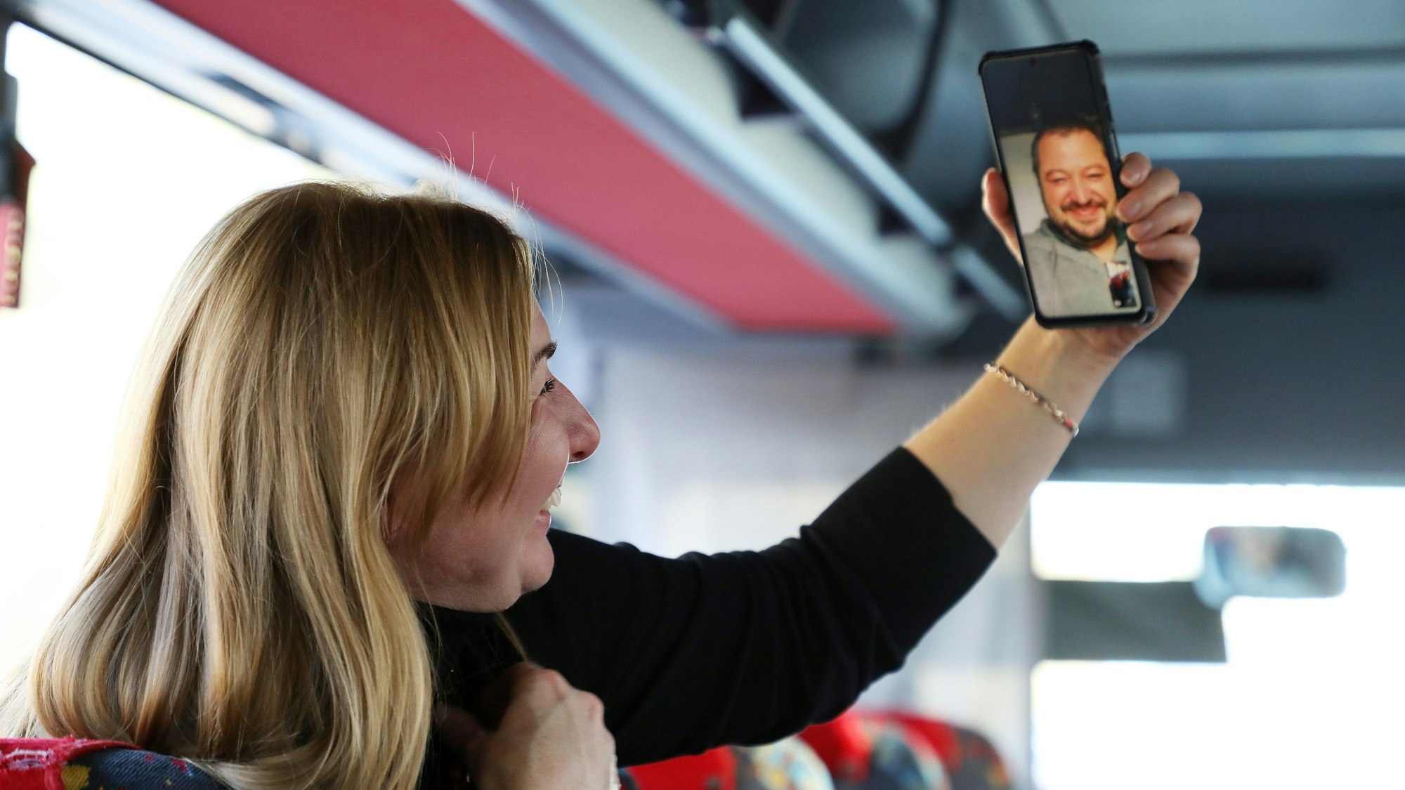 Tanja Rybakova hält ihr Handy in die Höhe, auf dessen Bildschirm ihr Mann in einem Videotelefonat zu sehen ist.