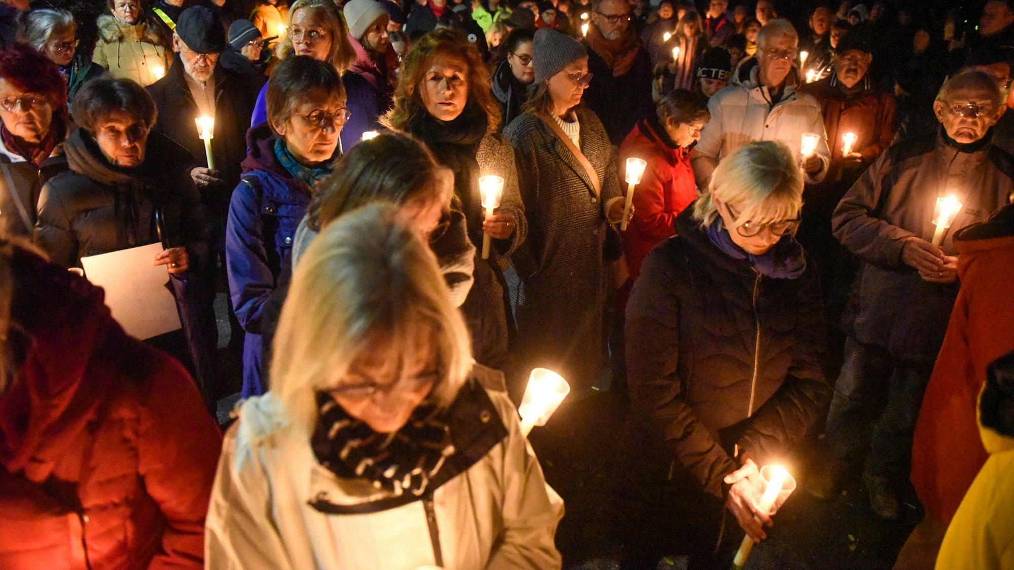 Auf dem Foto sind Teilnehmende des Schweigegangs zu sehen. Sie halten Kerzen in ihren Händen.