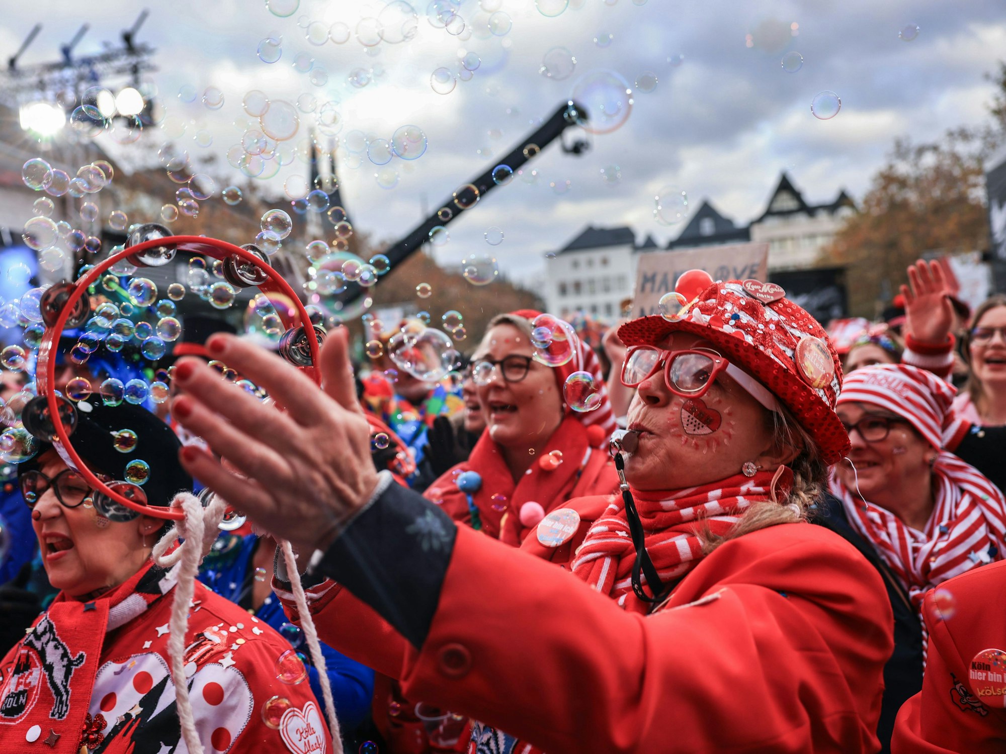 Menschen in roten Kostümen feiern auf dem Heumarkt in Köln