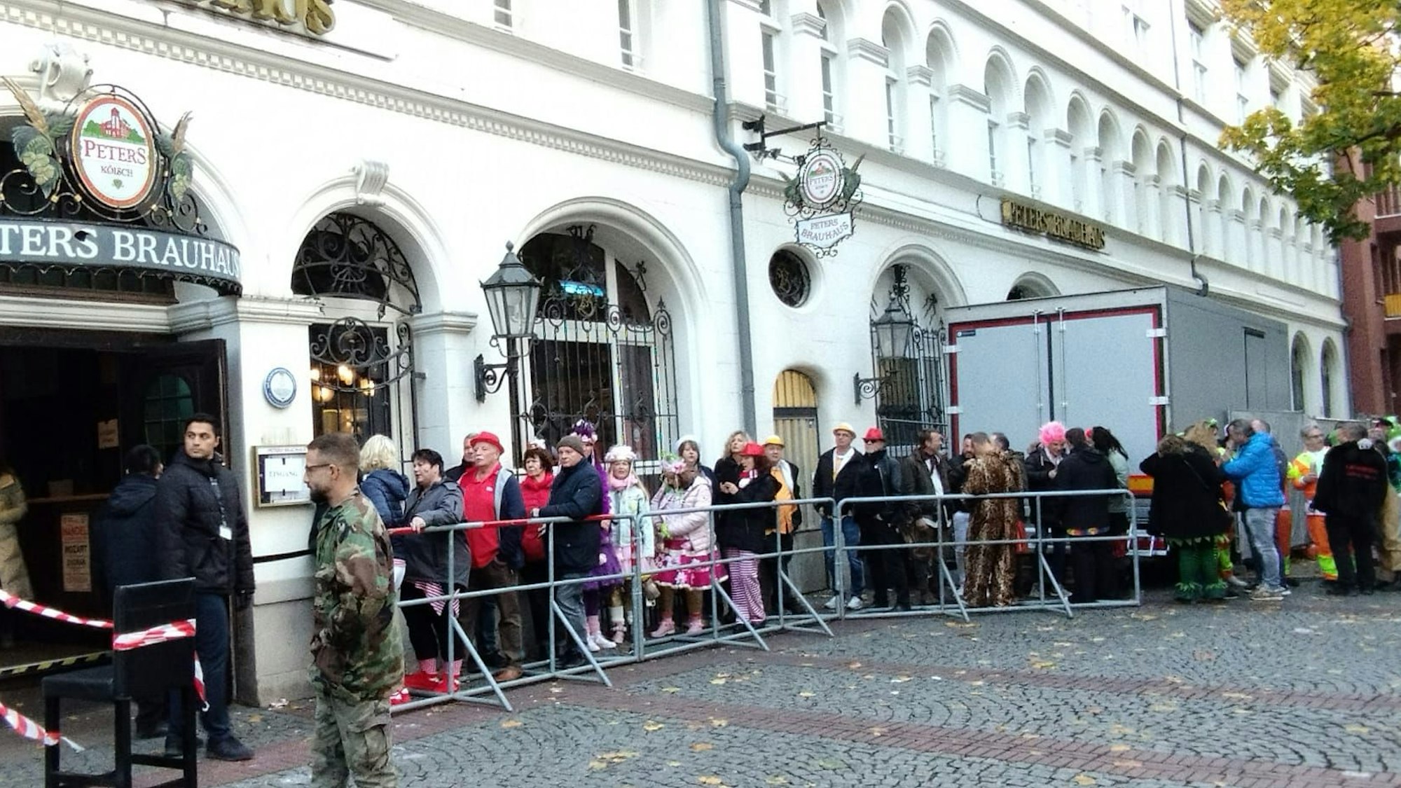 Einige Menschen in einer Warteschlange vor einem Brauhaus in Köln.