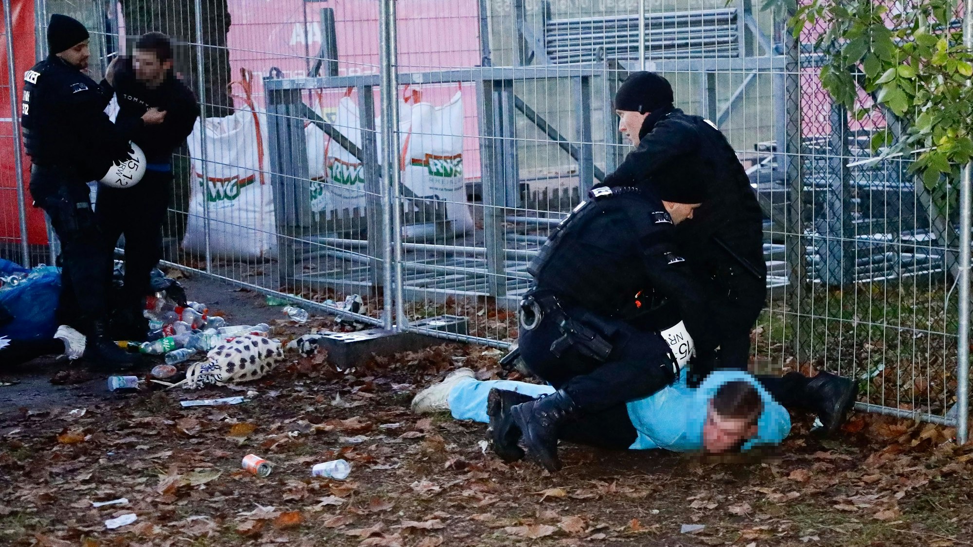Polizeibeamte fixieren am Abend eine Person in der Nähe des Aachener Weihers auf dem Boden.