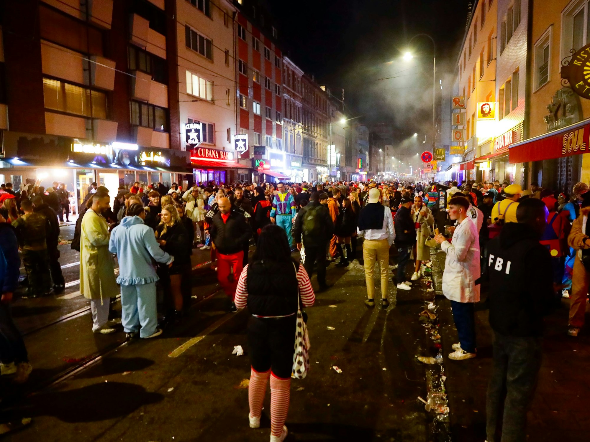 Menschen feiern in der Dunkelheit auf der Zülpicher Straße in Köln.