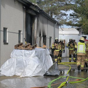 Feuerwehrleute gehen unter Atemschutz über das Firmengelände,