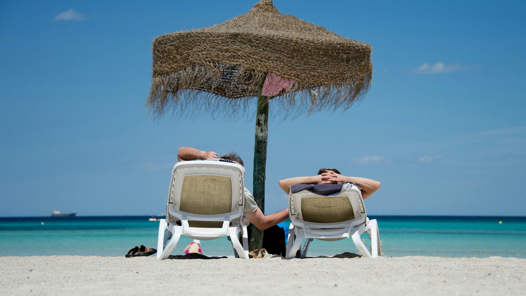 Zwei Urlaubende liegen in unserem Symbolbild am Strand von Mallorca (Archivbild 2013): Eine Reiseveranstalterin auf Mallorca hat Frischvermählte um ihr Geld gebracht.