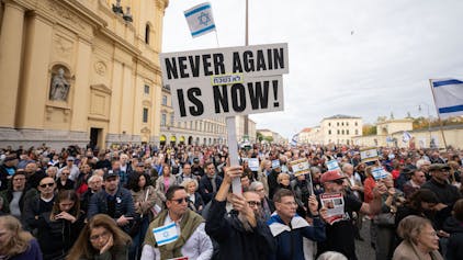 Ein Teilnehmer der Kundgebung "Solidarität mit Israel - Gegen gegen Terror, Hass und Antisemitismus" hält ein Schild mit der Aufschrift "NEVER AGAIN IS NOW!" in die Höhe.&nbsp;