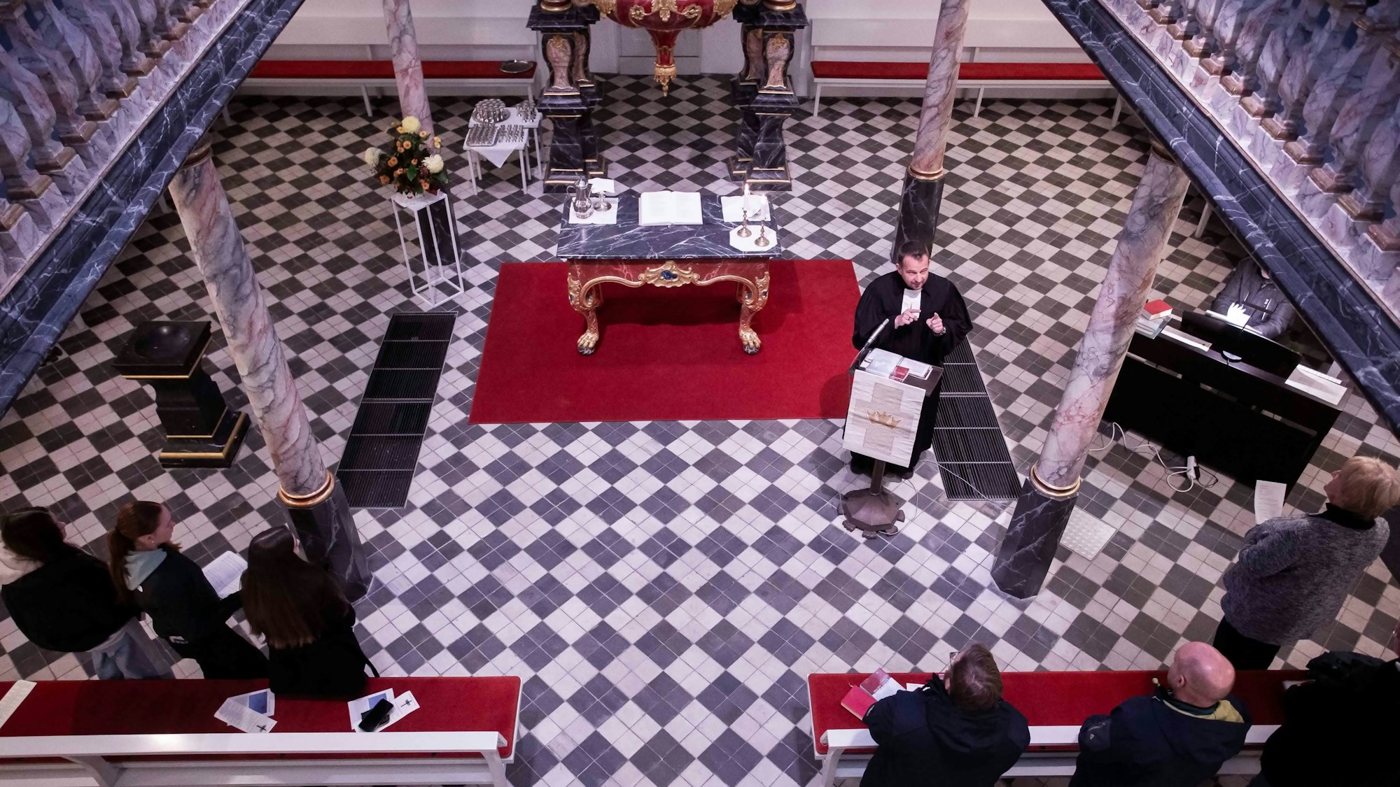 Sicht von einer Orgelempore auf einen Kirchenraum darunter. Ein Pfarrer steht an einem Ambo.