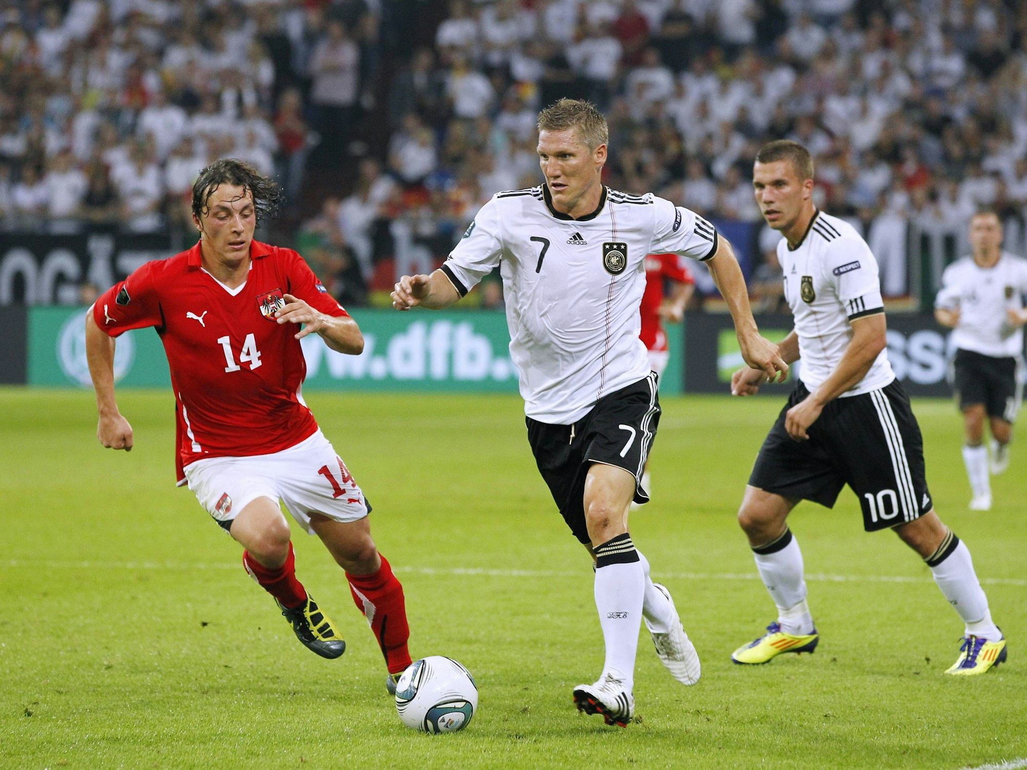 Bastian Schweinsteiger (r.) wird von Baumgartlinger (li.) verfolgt. Podolski steht im Hintergrund.