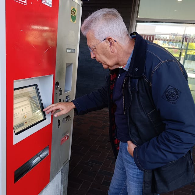 Ein Mann steht an einem Ticketautomaten.
