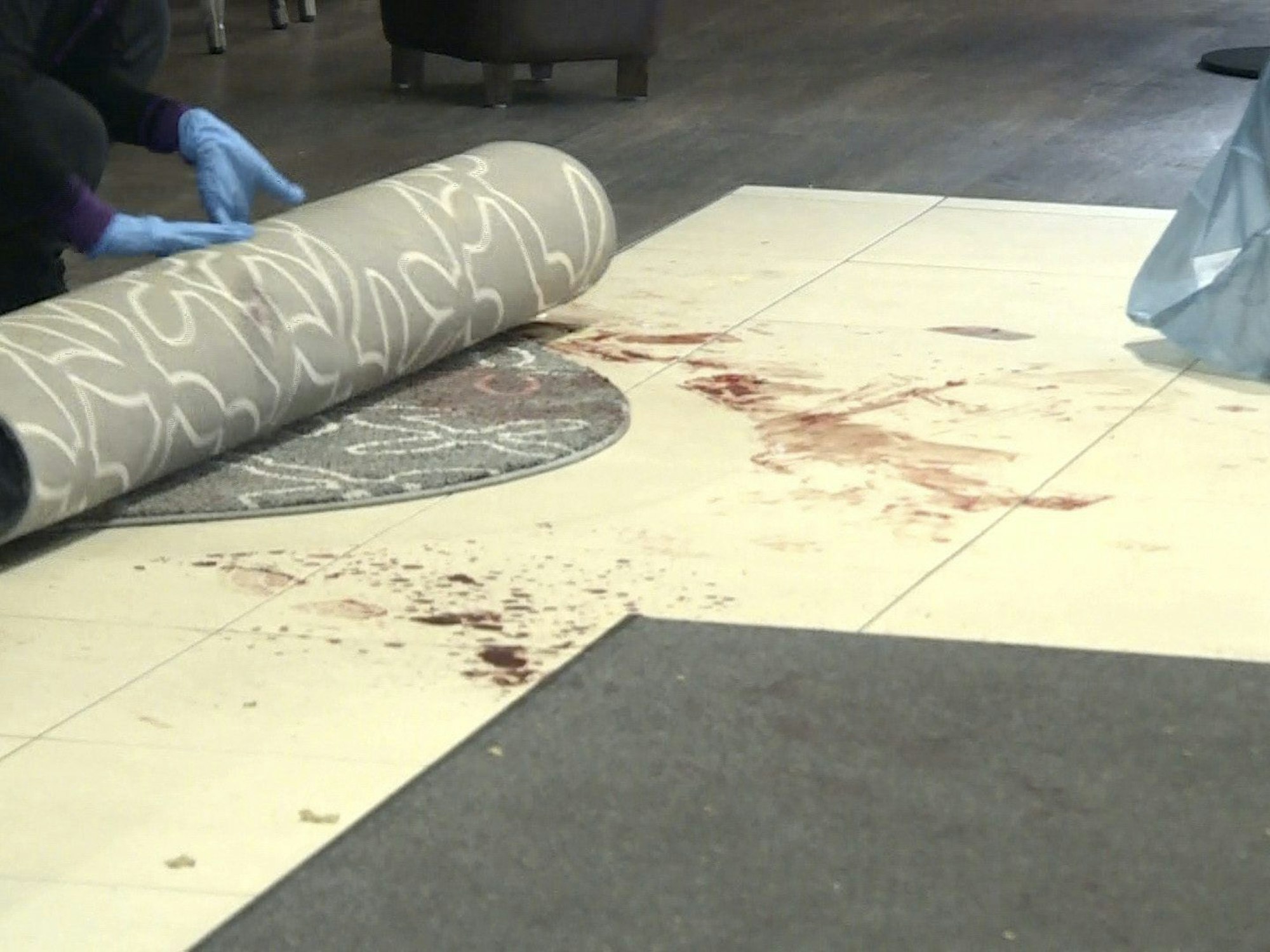 Ein Mitarbeiter der Spurensicherung rollt einen blutigen Teppich ein, im Eingangsbereich eines Hotels. Hier wurde am 14. November 2023 ein Mann erstochen.