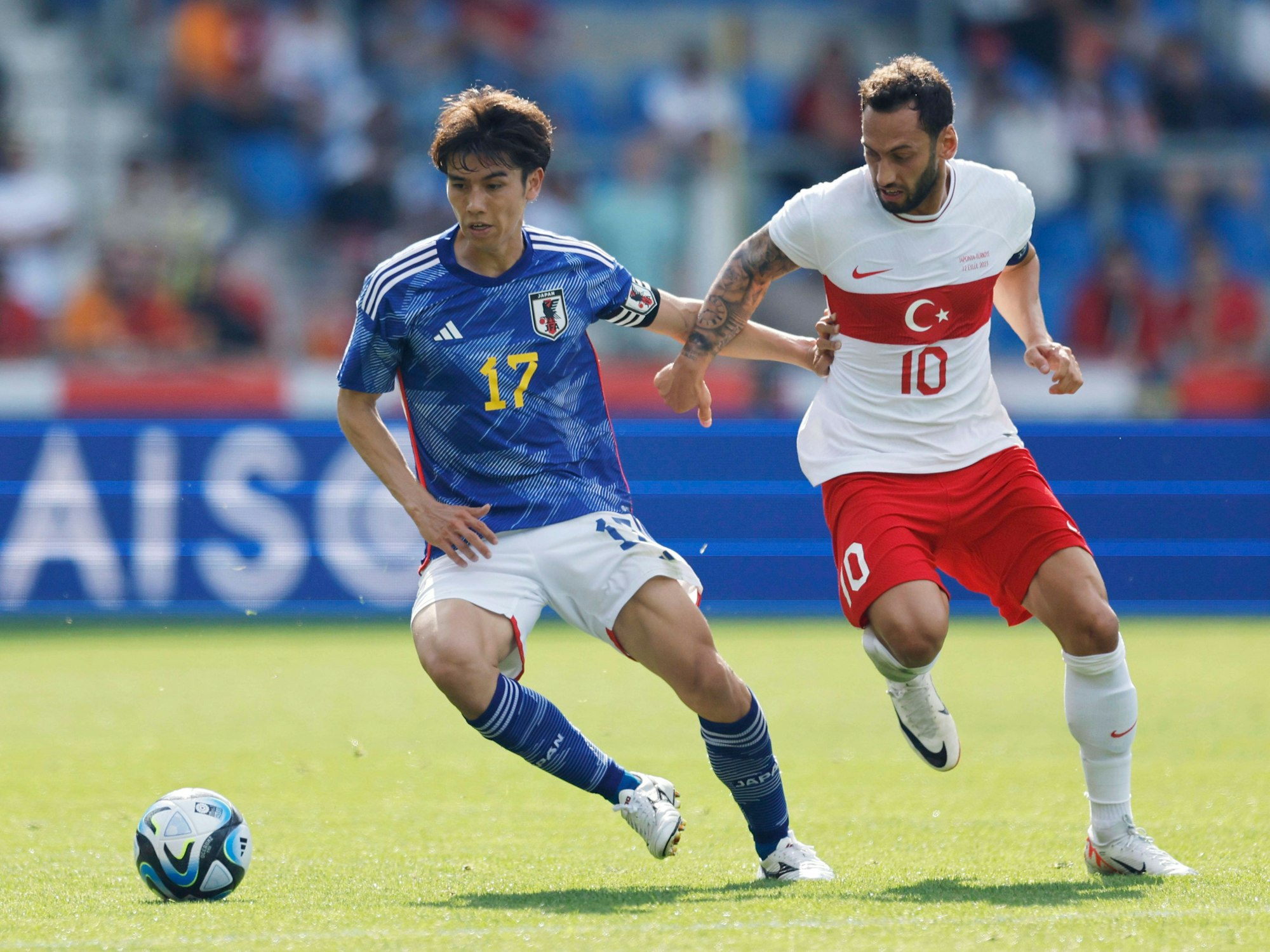 Düsseldorf-Dribbler Ao Tanaka (l.), hier im Zweikampf mit Hakan Calhanoglu am 12. September 2023, kämpft mit Japan um ein Ticket für die WM 2026.