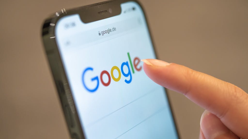 Eine Frau hält ihr Handy in der Hand, auf dem die Google-Seite im Browser zu sehen ist.