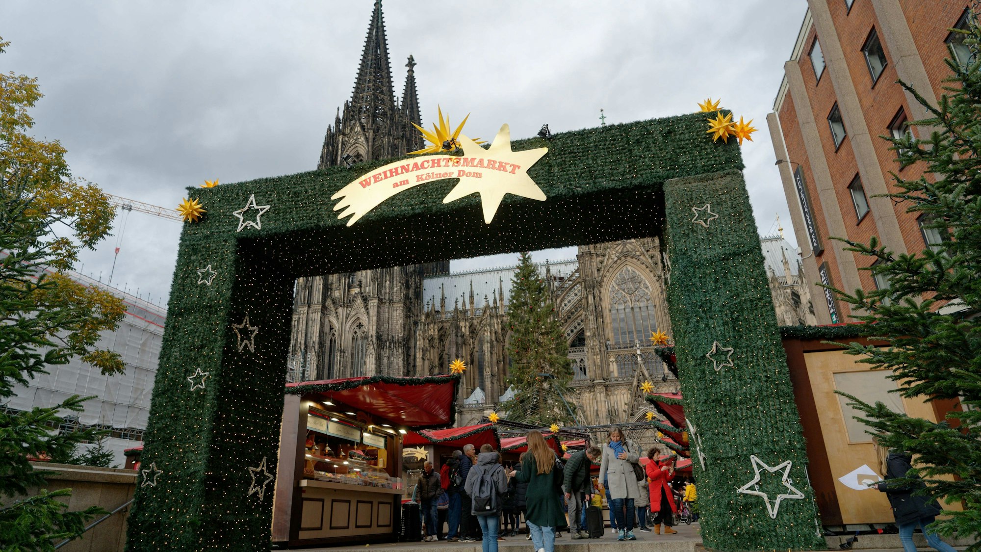 Besucher gehen durch den Weihnachtsmarkt vor dem Kölner Dom.