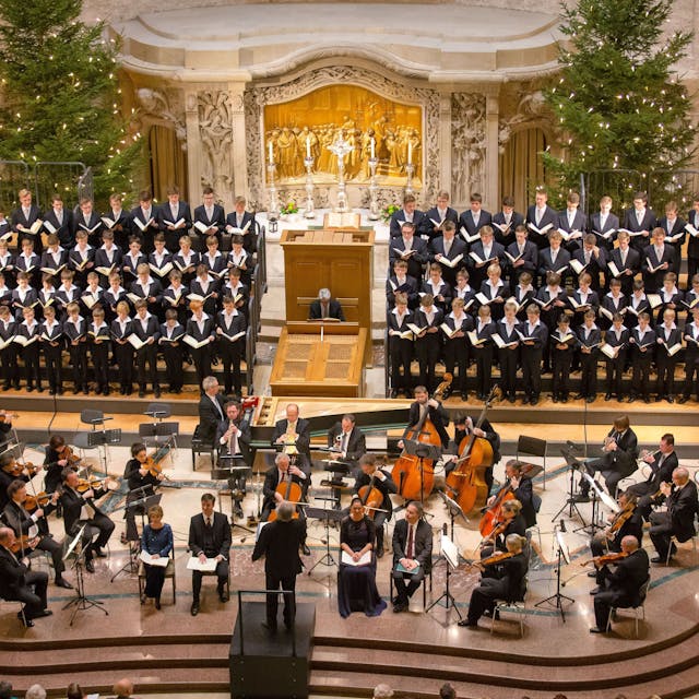 Aus der Vogelperspektive sieht man das das Orchester und den Chor in der Dresdner Kreuzkirche. Hinter dem Chor sind zwei geschmückte Tannenbäume.